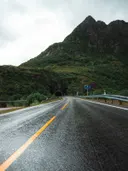 Weg door de bergen die naar een tunnel leidt onder bewolkte lucht.