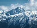 Besneeuwde bergketen onder een blauwe lucht met wolken