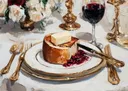Feestelijk gedekte tafel met brood, boter, granaatappelpitjes, kaarsen en een glas rode wijn