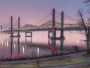 Moderne tuibrug over een rivier gehuld in ochtendmist met lichtreflecties in het water.