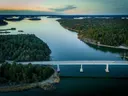 Luchtfoto van een brug over water tussen beboste eilanden bij schemering.