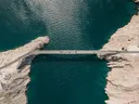 Luchtfoto van een brug tussen twee rotskusten boven turkoois water, met auto's op het wegdek.