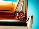Close-up van het chromen achterlicht en de oranje carrosserie van een klassieke auto.