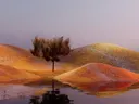 Gestileerd landschap met glooiende heuvels, een enkele boom en een waterspiegeling onder een roze lucht.