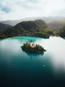 Luchtfoto van een eilandje met kerk in een turkoois meer, omringd door bergen.