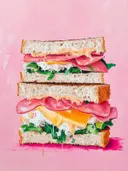Schilderij van een dubbele sandwich met ham, kaas en sla.