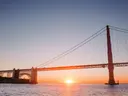 De Golden Gate Bridge gefotografeerd tegen een ondergaande zon die net boven de horizon staat.