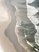 Luchtfoto van golven en schuim op een zandstrand vanuit de lucht