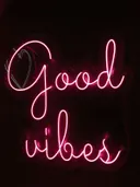 Foto van een roze neonbord met de tekst Good Vibes tegen een donkere achtergrond.