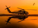 Helikopter op een nat platform bij een oranje zonsondergang
