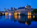 Verlicht historisch gebouwencomplex aan het water tijdens de schemering.