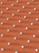 Een groot aantal honkballen verspreid over een oranjerode ondergrond met lange schaduwen.