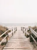 Foto van een houten strandpad tussen duingras met uitzicht op zee