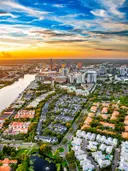 Luchtfoto van een voorstad aan het water tijdens zonsondergang met een stadsskyline