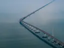 Luchtfoto van een lange brug die door de mist over water slingert.