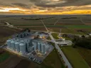 Luchtfoto van graansilo's tussen landbouwvelden bij zonsondergang.