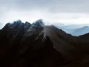 Ruige, donkere bergtoppen gehuld in mist en laaghangende wolken.