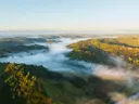 Luchtfoto van mistige, beboste heuvels bij zonsopkomst