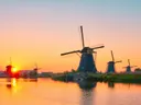 Rij Nederlandse windmolens langs het water bij Kinderdijk tijdens zonsondergang.