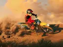 Motorcrossrijder in rode outfit rijdt door een grote stofwolk bij zonsondergang.
