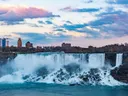 Niagara Falls met stromend water en een stadsskyline op de achtergrond