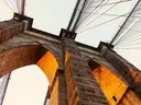 Onderaanzicht van de stenen pijler en kabels van een historische hangbrug.