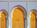 Drie sierlijke gouden poorten met kleurrijk mozaïekpatroon aan een Marokkaans gebouw