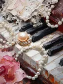 Schilderij van een parelketting en broche op pianotoetsen