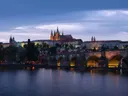 Skyline van Praag met kasteel en brug over de rivier bij avondschemering.
