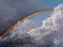 Schilderij van een regenboog met een blauwe luchtopening tussen wolken