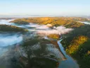 Luchtfoto van een rivier door mistige, beboste heuvels met een brug