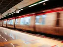 Metrostation met een voorbijrazende trein in bewegingsonscherpte en een klok aan het plafond.