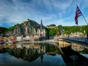Historisch stadje met kerktoren en rotsformatie weerspiegeld in het water.