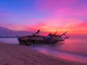 Vervallen scheepswrak op het strand bij een kleurrijke zonsondergang