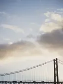 Silhouet van een hangbrug tegen een bewolkte lucht