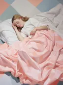 Realistisch portret van een slapende vrouw in bed met wit shirt en roze geruit dekbed.