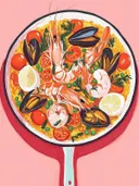 Schilderij van een paellapan met garnalen, mosselen, tomaten en citroen.
