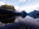 Besneeuwde bergtoppen van een fjord weerspiegeld in het spiegelgladde water.