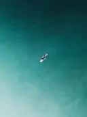 Luchtfoto van een surfer die drijft op een surfboard in turquoise water
