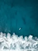 Luchtfoto van een surfer op een surfboard in blauw zeewater bij golven