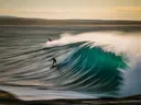 Twee surfers op een grote groene golf in zee.