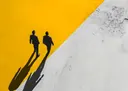 Grafische silhouetten van twee mannen in pak die weglopen met lange schaduwen op geel-witte ondergrond
