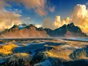 Bergketen Vestrahorn in IJsland met zwart zandstrand en wolken bij zonsopgang.