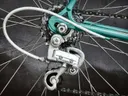 Close-up van het achterwiel en de versnellingsmechaniek van een vintage racefiets met een mintgroen frame.