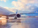 Passagiersvliegtuig op een nat platform onder een bewolkte lucht bij zonsondergang