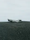 Verroest vliegtuigwrak op een donkere vlakte onder een bewolkte lucht