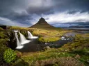 Watervallen met de puntige Kirkjufell-berg op de achtergrond onder een bewolkte lucht