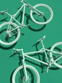 Twee zwevende fietsen tegen een smaragdgroene achtergrond